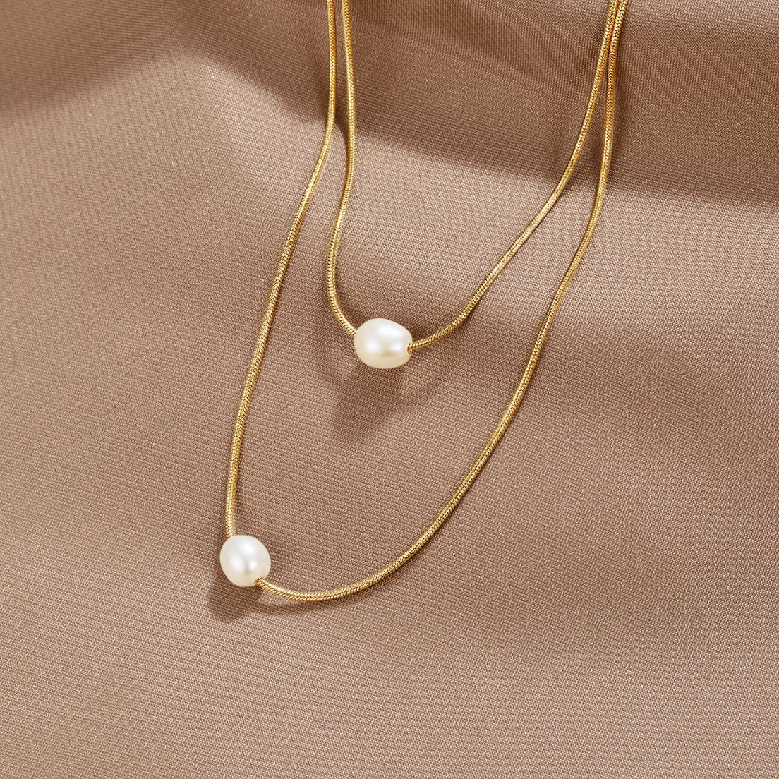 Sabine – Two-layer gold chain with a dark stone.