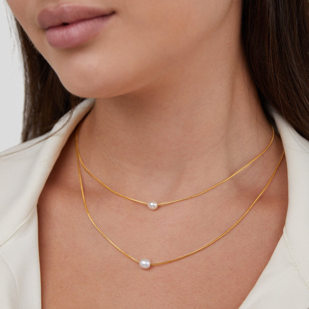 Sabine – Two-layer gold chain with a dark stone.